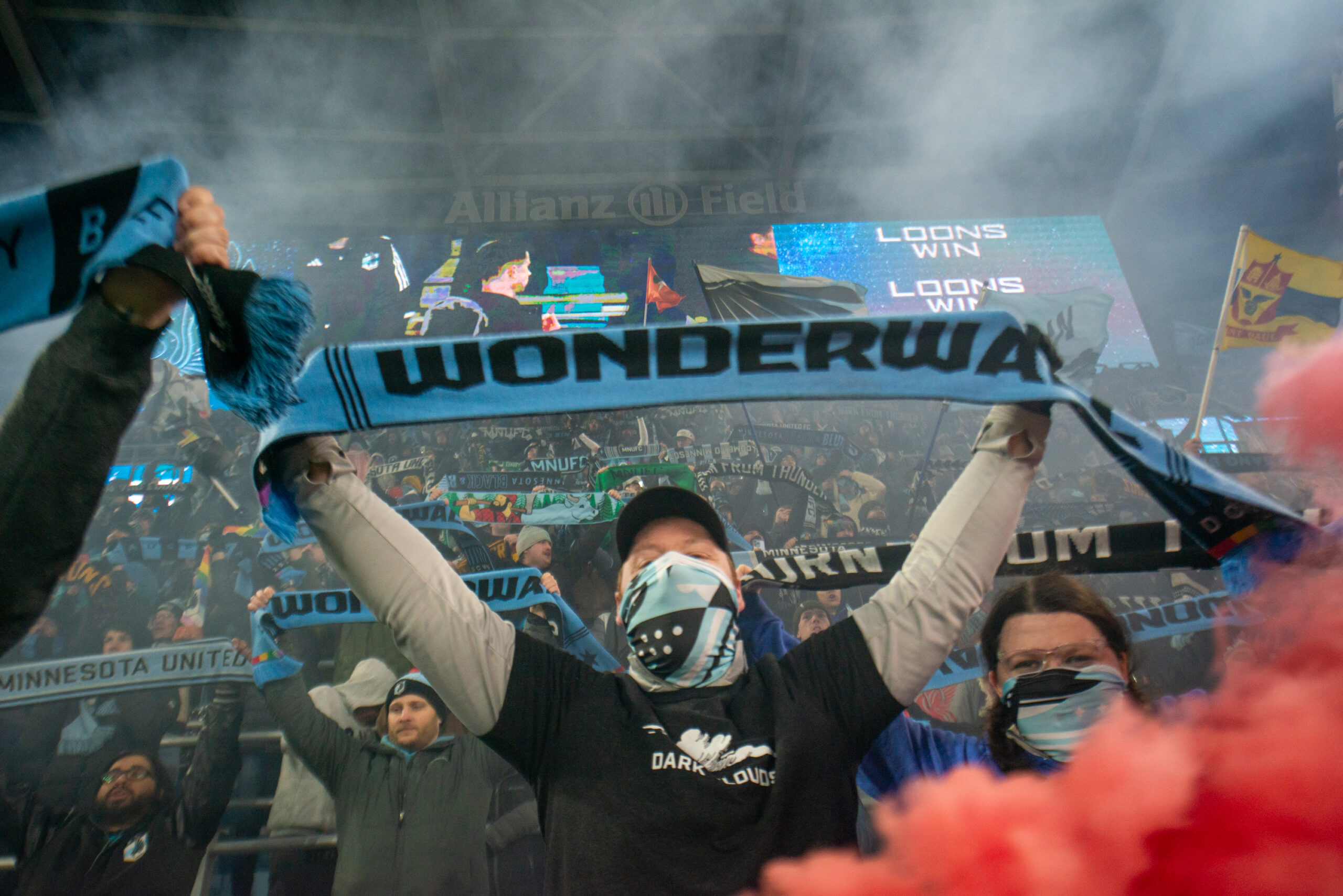 Supporters in the Wonderwall standing-only section hold up scarves saying