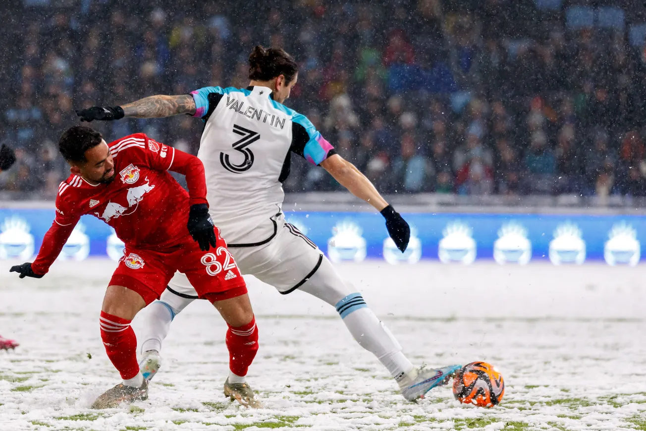 The players battle for possession on a snow covered field.
