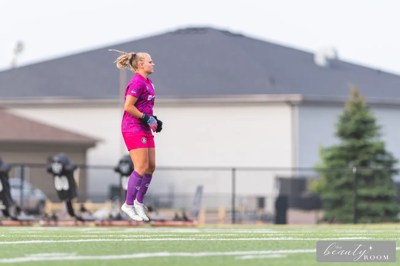 A white woman in all pink kit jumping