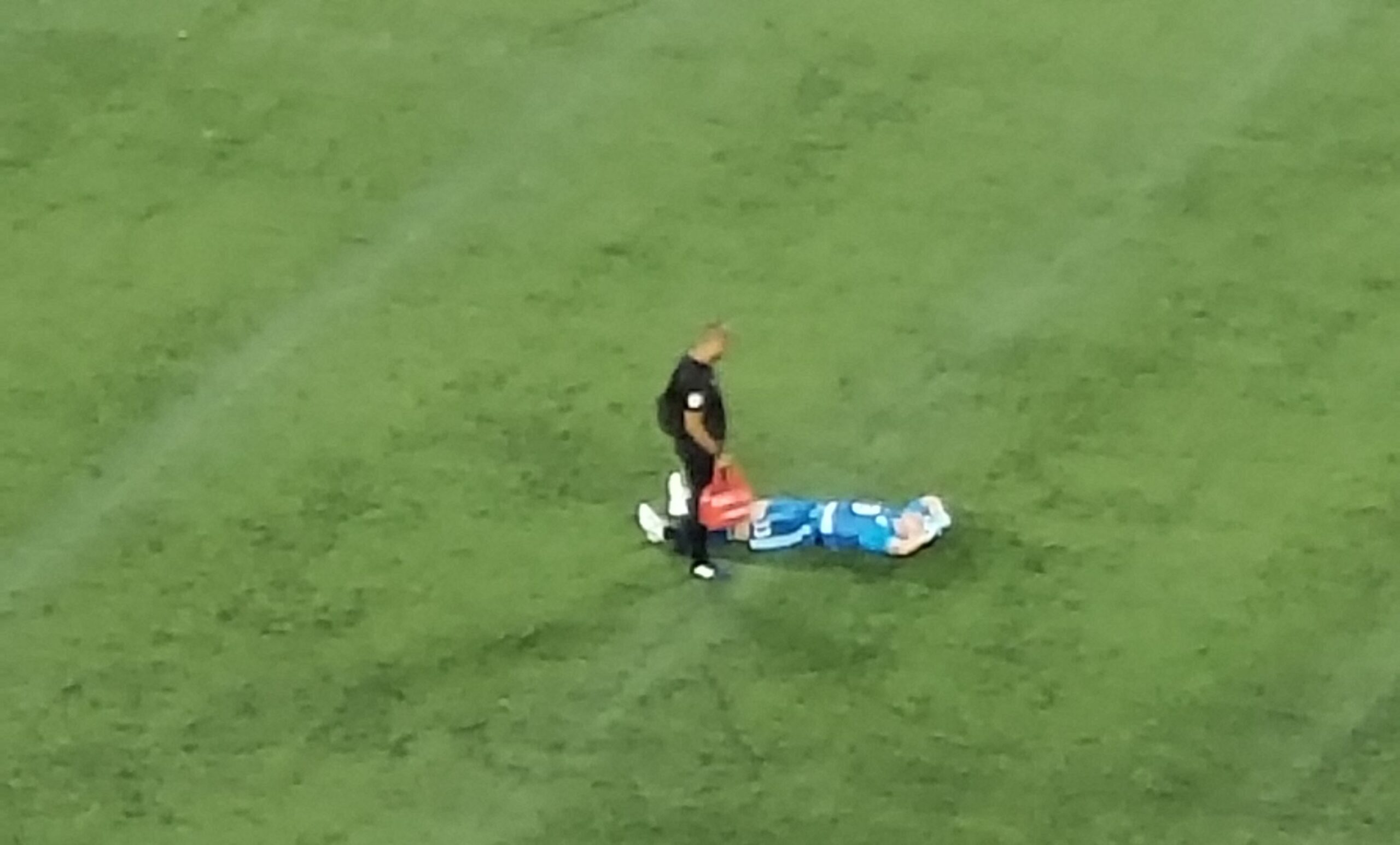 Bobby Shuttleworth lays face up on the pitch with an athletic trainer standing over him.